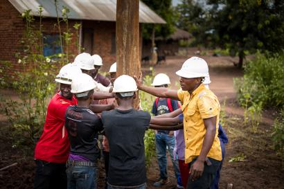 Several men hoisting a utility pole