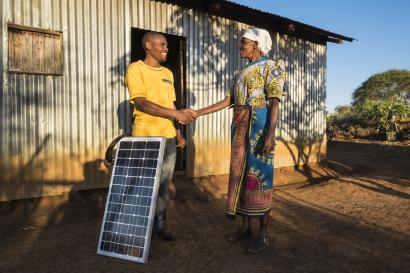 Man and woman shaking hands in front of house with solar panel