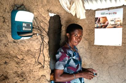 Woman stands in room with solar monitor on the wall, along with a calendar.