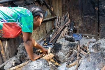 Person bending over to pick up charred wood