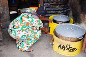 Woman bending to open cooking pot