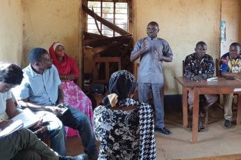 People in a room watching a man speaking