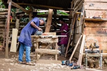 A person in a workshop sawing wood