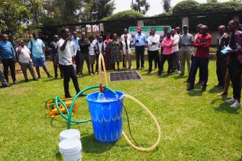 Rwanda community members view a solar irrigation demonstration outside.