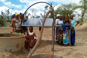 group of people standing near a solar panel