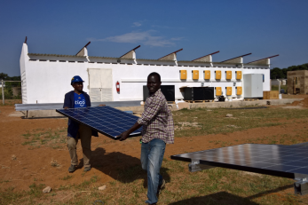 two men carrying a solar panel