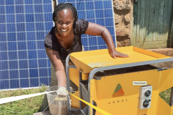 woman holding grain from solar mill