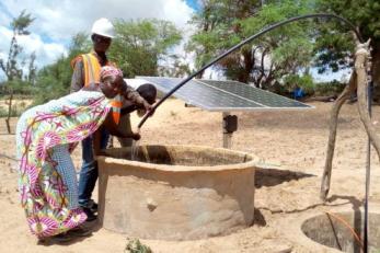 people looking into a solar-powered well