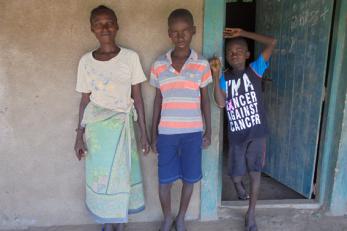 a woman and two children standing in front of an open door
