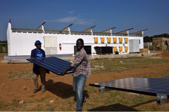 two men carrying a solar panel
