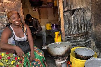 woman seated near cooking pots