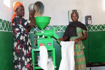two women pouring grain into a mill