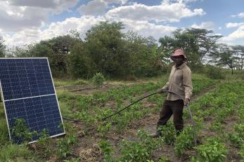man standing in field with solar panel