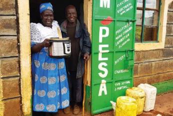 people standing in doorway holding cooking pot