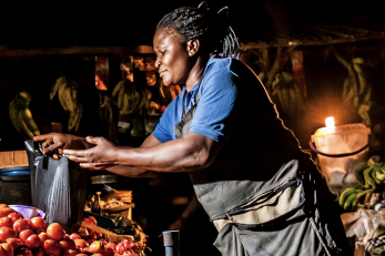 woman holding a watering can over produce