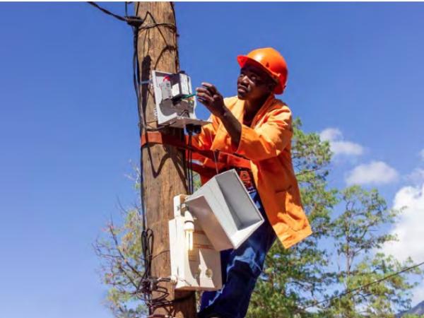Ugandan working on installing power component on pole.