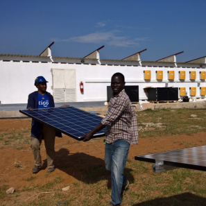 Two men carrying a solar panel