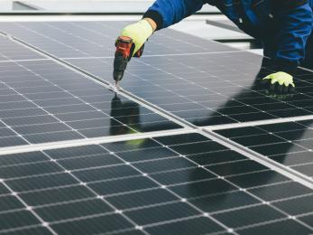 Worker drilling solar panel