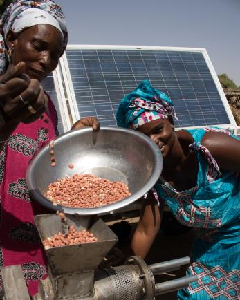 two women pouring food with solar panel in the background