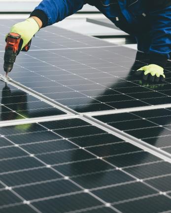 Worker drilling solar panel