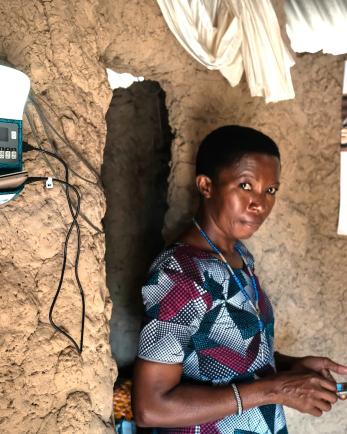 Woman stands in room with solar monitor on the wall, along with a calendar.