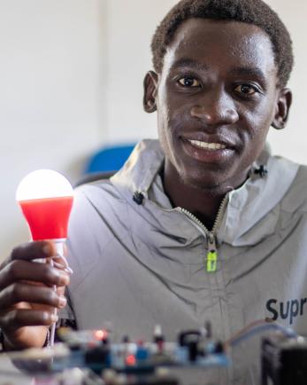 Man holding LED lightbulb, smiling.