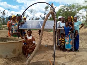 Group of people standing near a solar panel