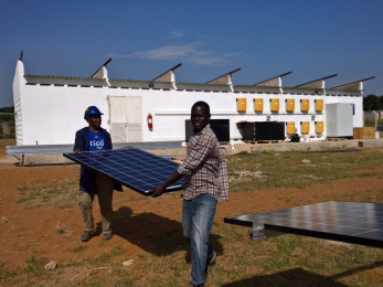 Two men carrying a solar panel