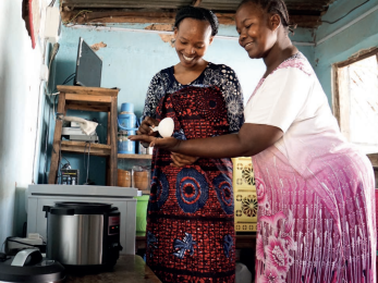 Two women scooping food from pot