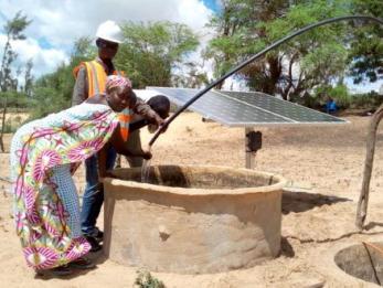 People looking into a solar-powered well