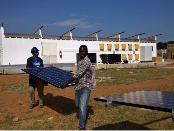 Two men carrying a solar panel