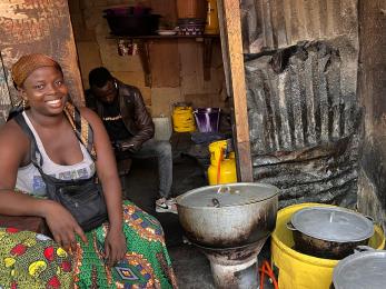 Woman seated near cooking pots