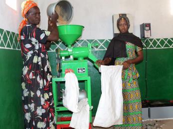 Two women pouring grain into a mill
