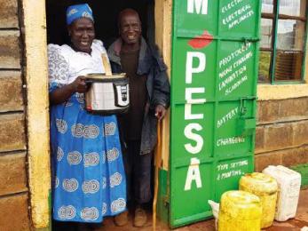 People standing in doorway holding cooking pot