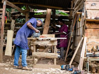 A person in a workshop sawing wood
